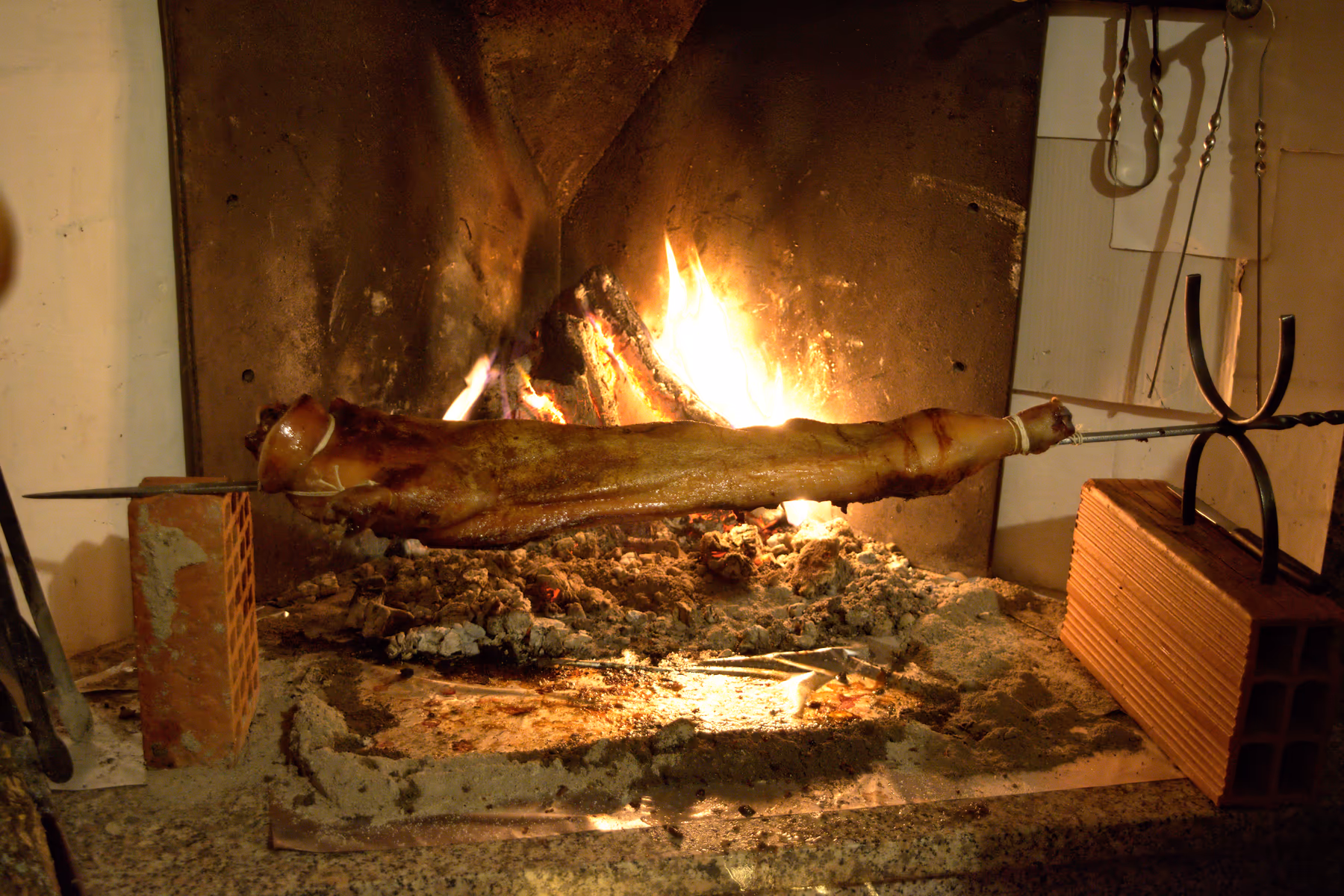 Porceddu, Sardinian suckling pig, roasting on a spit over a wood fire